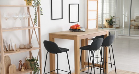 Photo of Bar stools near wooden table in room