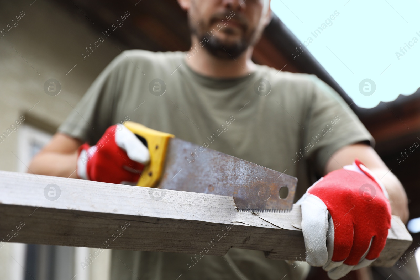 Photo of Man sawing wooden plank in backyard, closeup