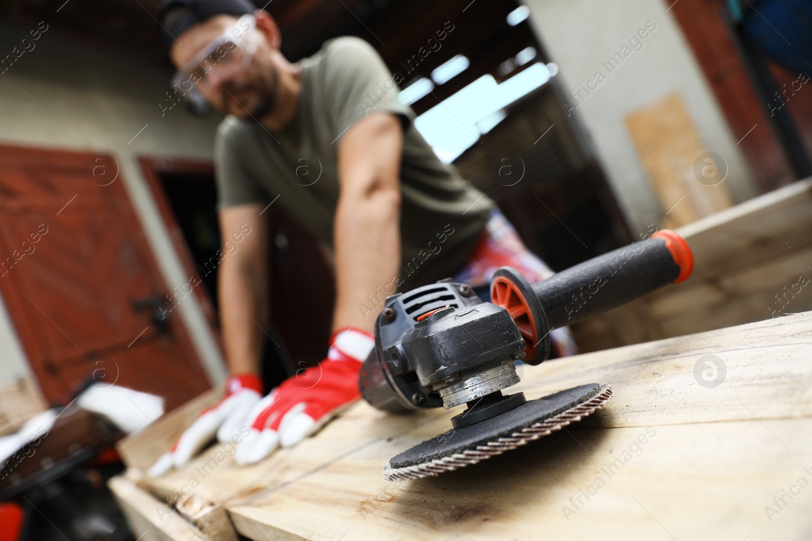 Photo of Man working with wood outdoors, focus on angle grinder