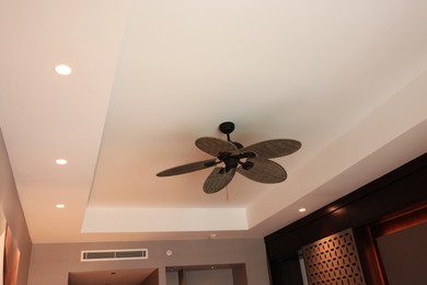 Photo of Modern ceiling fan indoors, low angle view