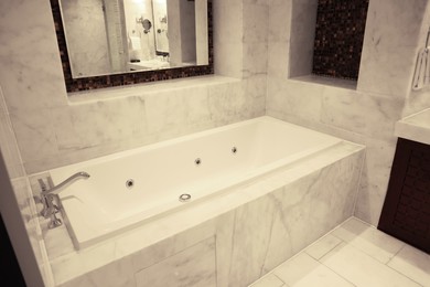 Stylish bathroom with marble bathtub and mirror in luxury hotel