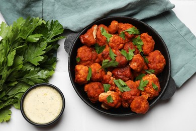 Photo of Baked cauliflower buffalo wings with parsley served on white table, flat lay