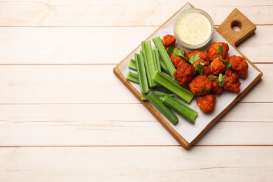 Photo of Baked cauliflower buffalo wings served on wooden table, top view. Space for text