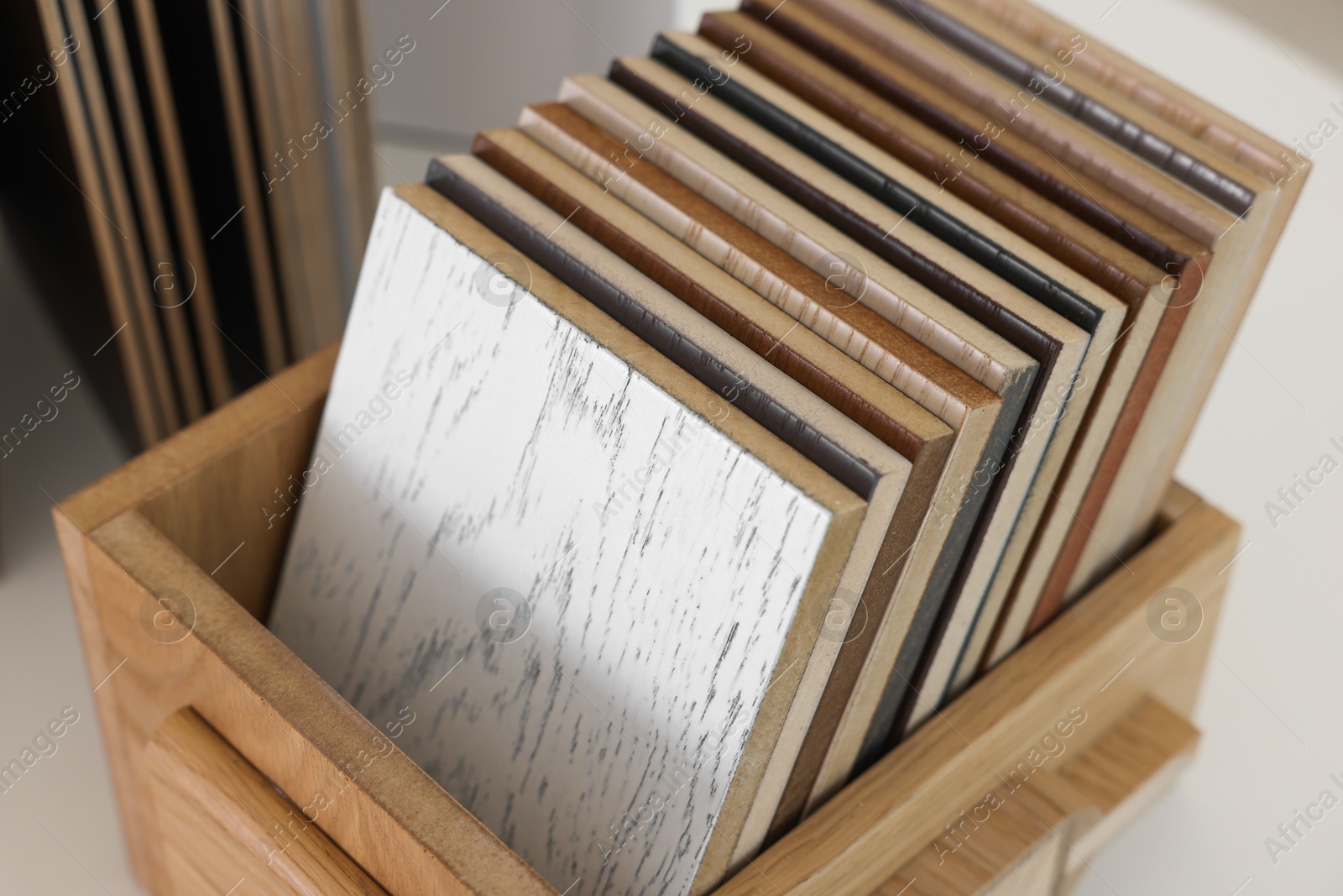 Photo of Different samples of wooden flooring on white table, closeup