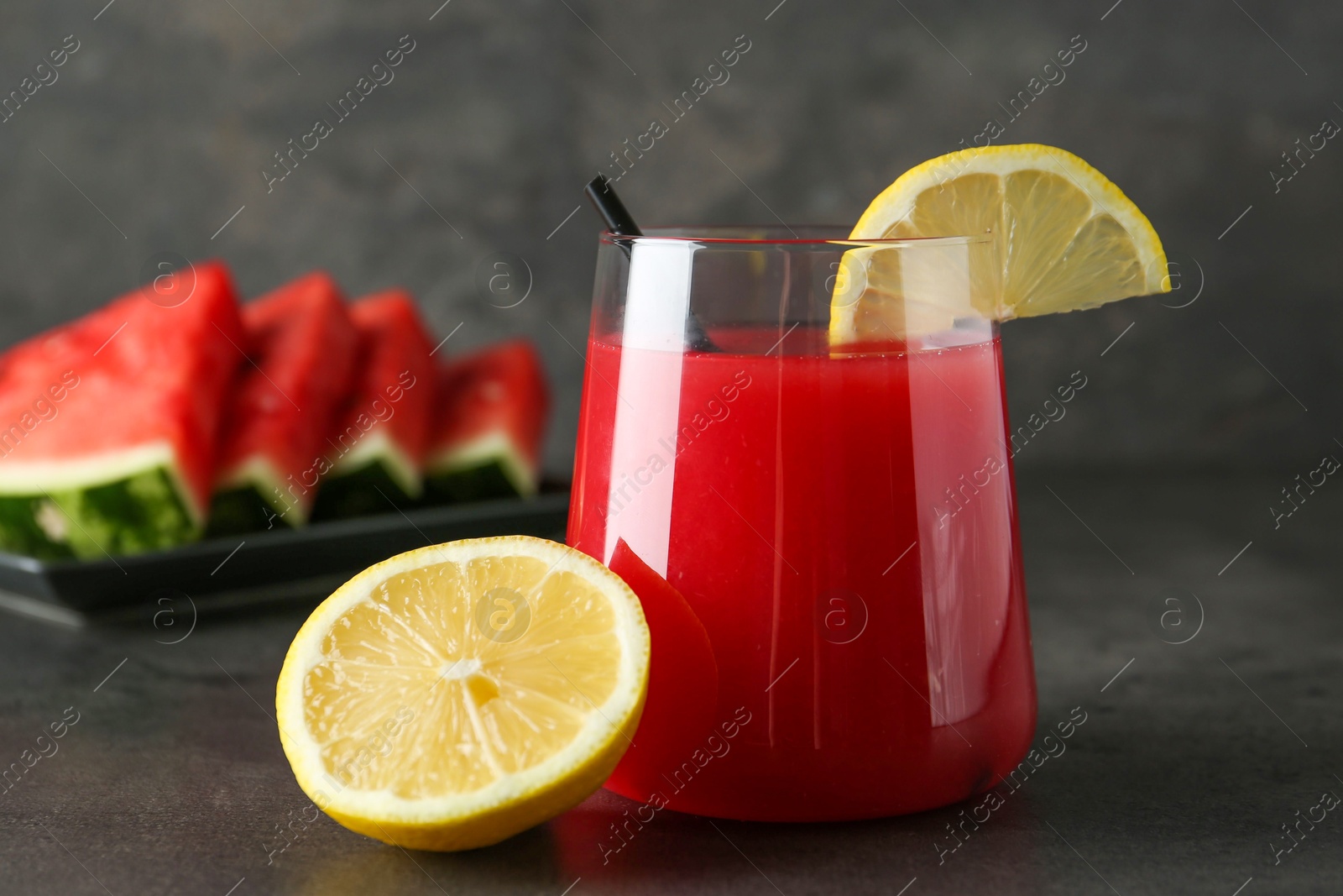 Photo of Delicious watermelon drink in glass and fresh fruits on dark grey table, closeup