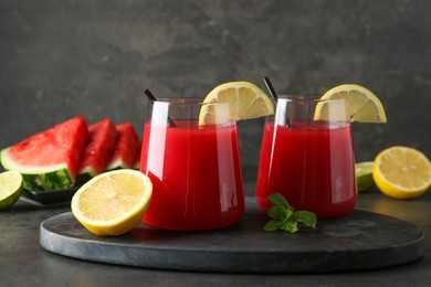 Photo of Delicious watermelon drink in glasses, fresh fruits and mint on grey table