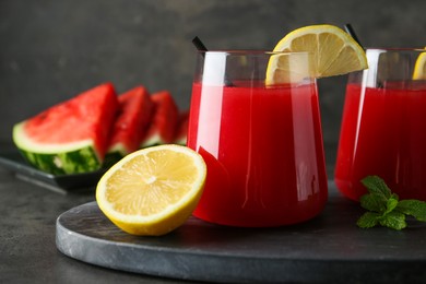 Photo of Delicious watermelon drink in glasses, fresh fruits and mint on grey table, closeup