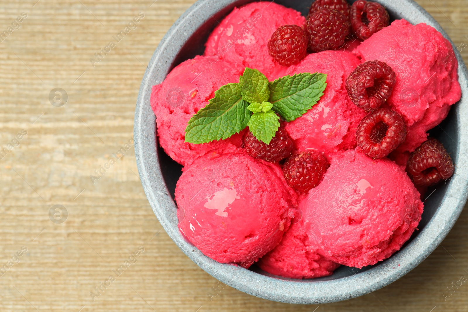 Photo of Delicious raspberry sorbet, fresh berries and mint in bowl on wooden table, top view