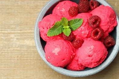 Photo of Delicious raspberry sorbet, fresh berries and mint in bowl on wooden table, top view