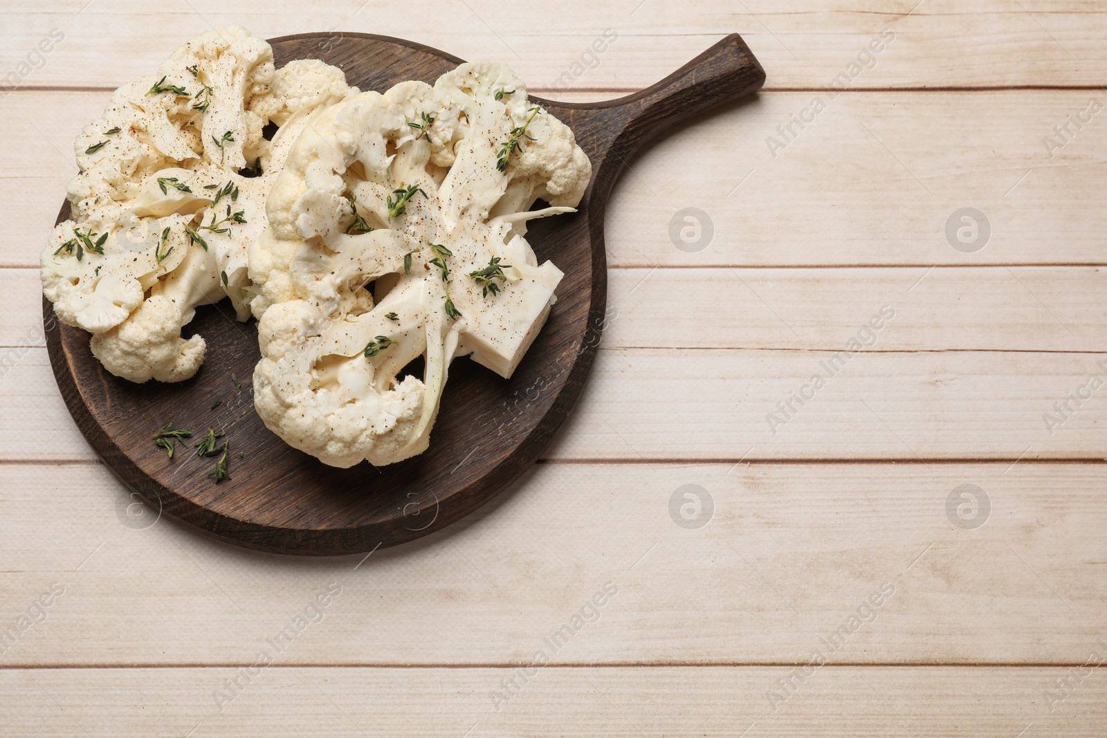 Photo of Uncooked cauliflower steaks with spices on wooden table, top view. Space for text