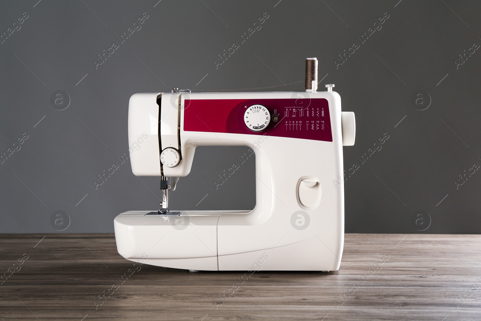 Photo of Sewing machine on wooden table against gray background