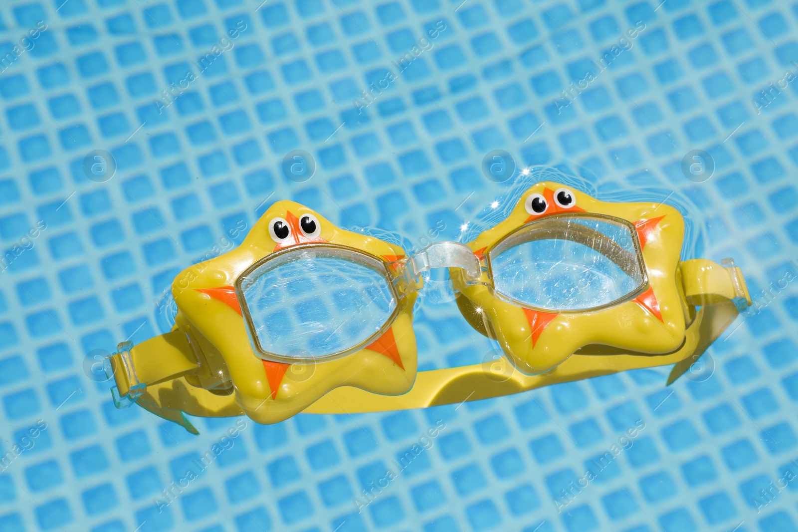 Photo of Cute swim goggles in swimming pool, closeup