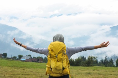 Photo of Young hiker with backpack in mountains, back view. Space for text