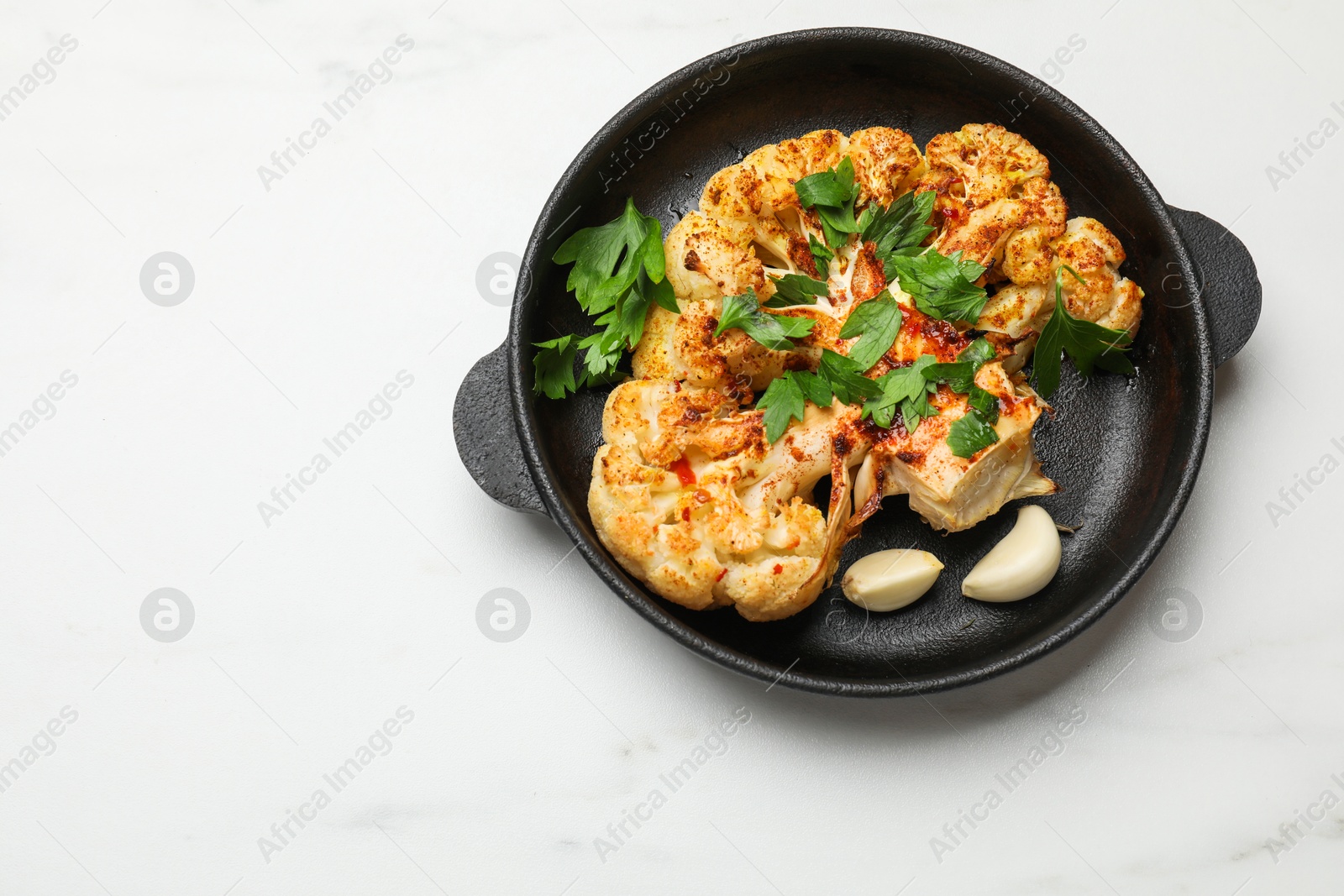 Photo of Tasty cauliflower steak in frying pan on white marble table, top view. Space for text