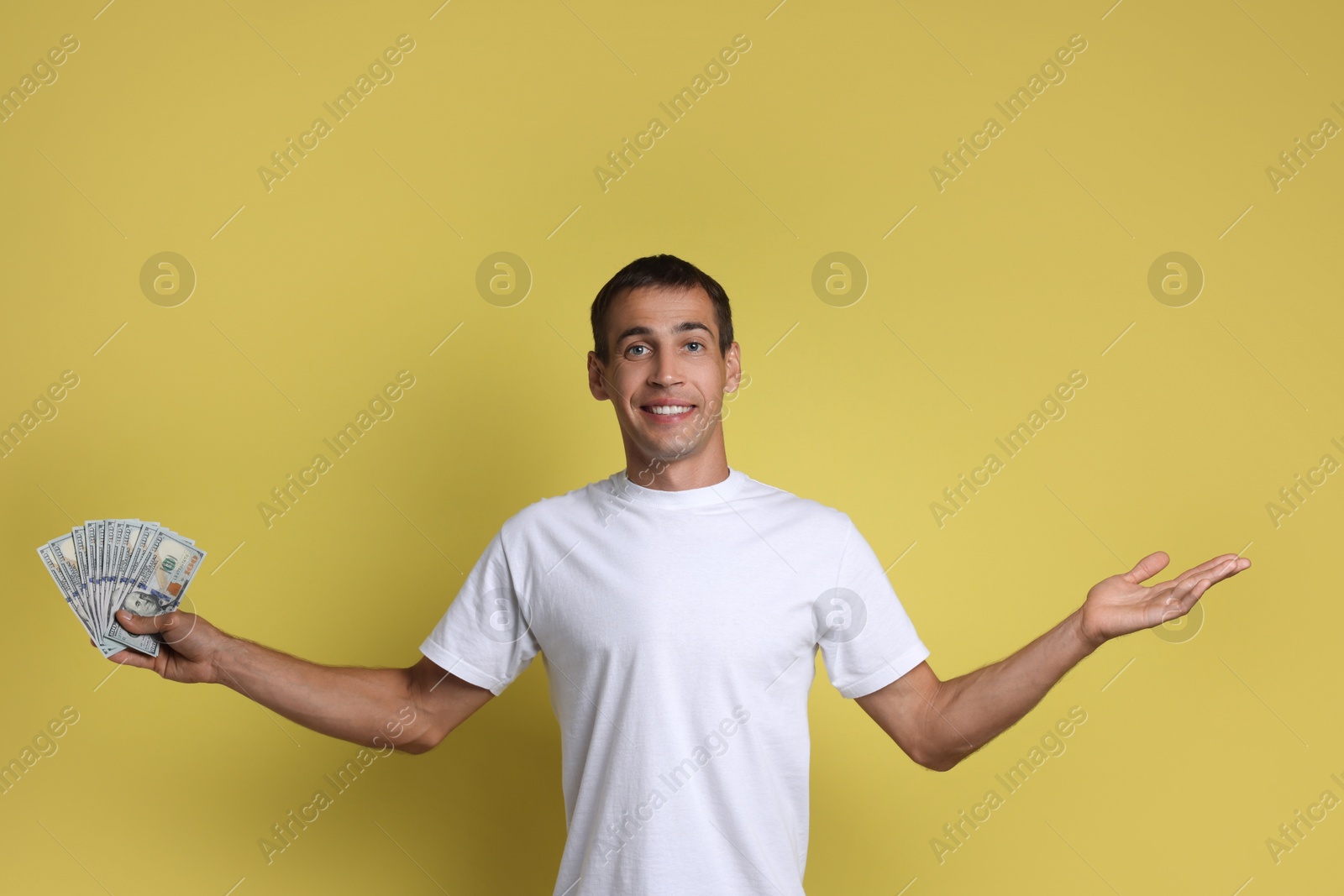 Photo of Man with dollar banknotes on yellow background