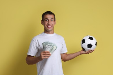 Happy man with money and soccer ball on yellow background