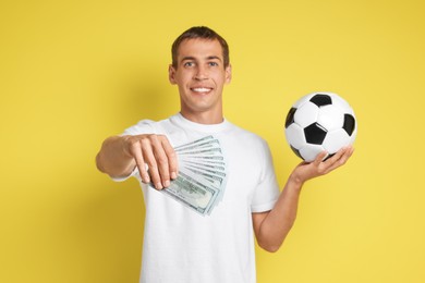 Photo of Happy man with money and soccer ball on yellow background