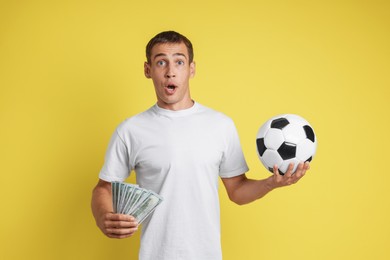 Confused man with money and soccer ball on yellow background