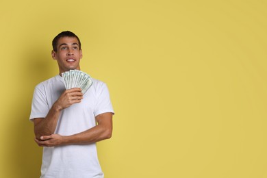 Photo of Man with dollar banknotes on yellow background, space for text