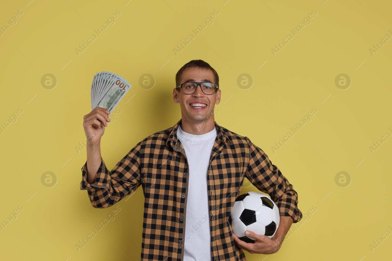 Photo of Happy man with money and soccer ball on yellow background