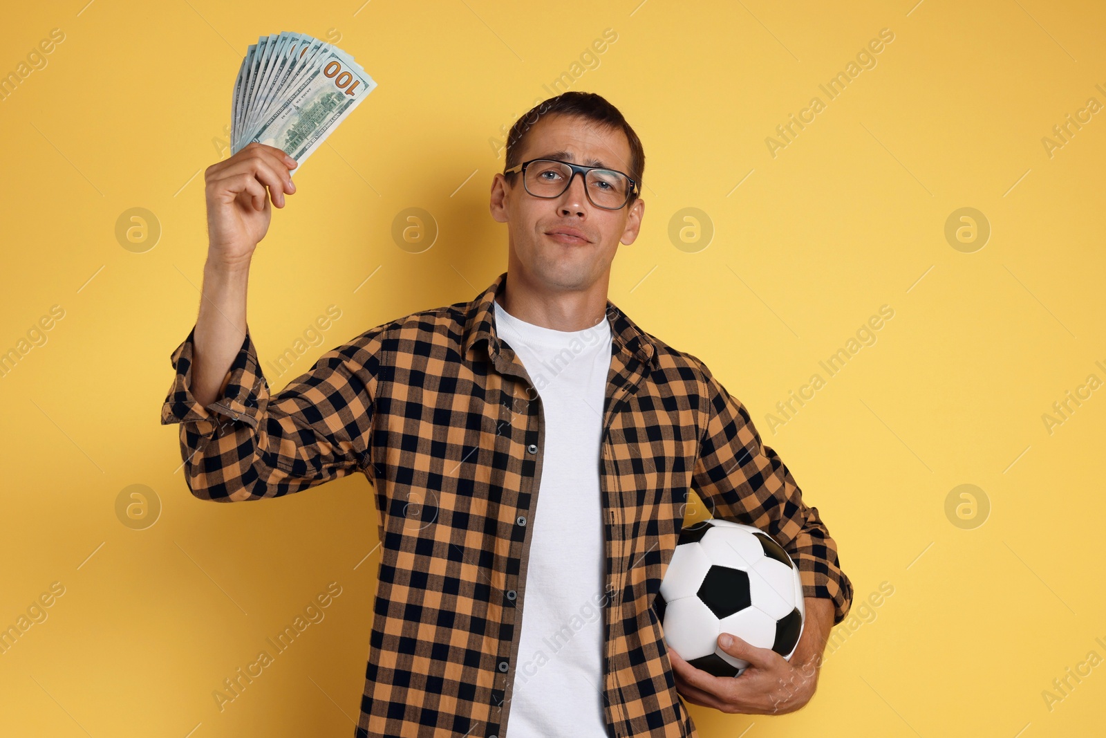 Photo of Man with money and soccer ball on yellow background