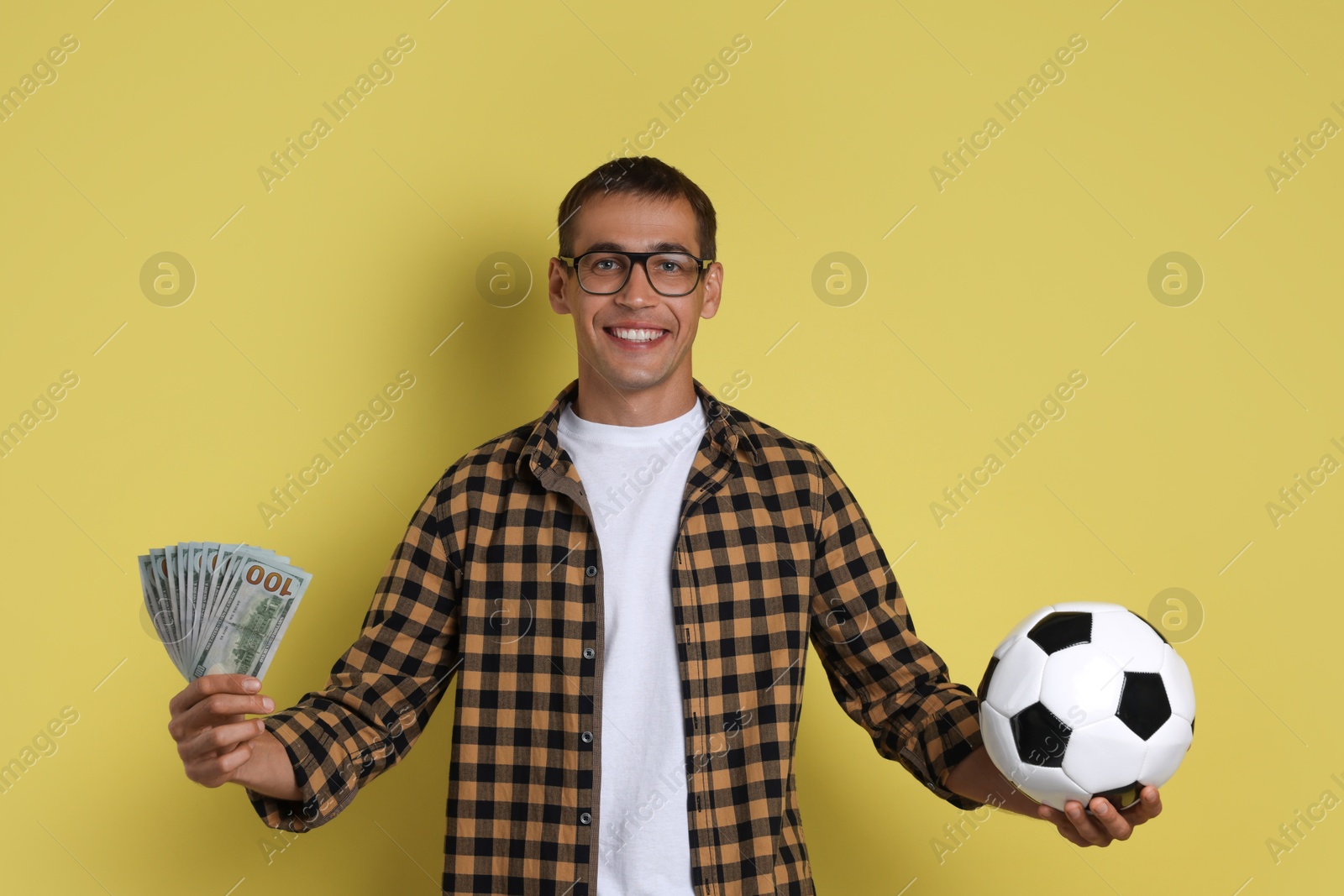 Photo of Happy man with money and soccer ball on yellow background