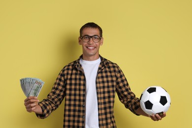 Happy man with money and soccer ball on yellow background