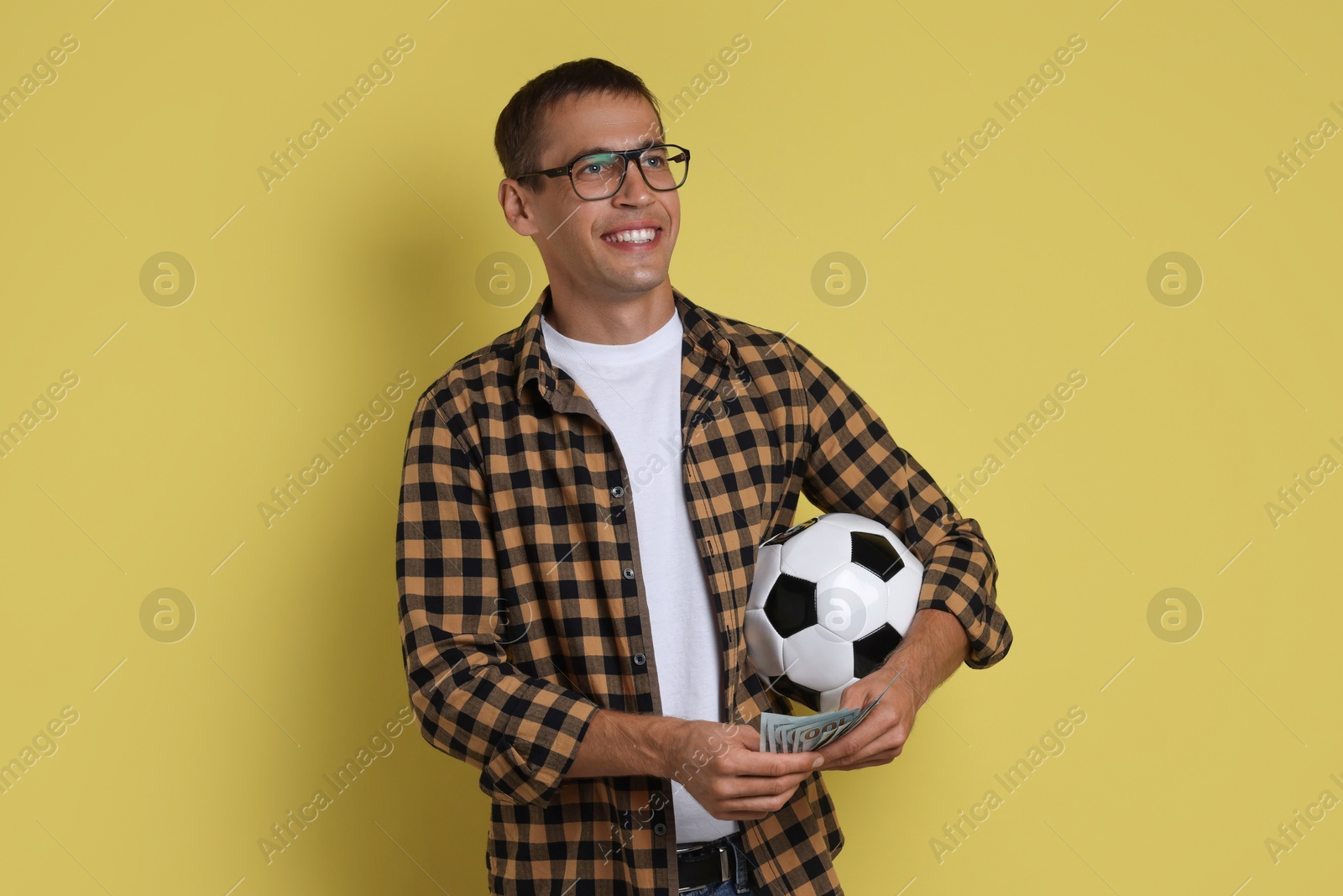 Photo of Happy man with money and soccer ball on yellow background