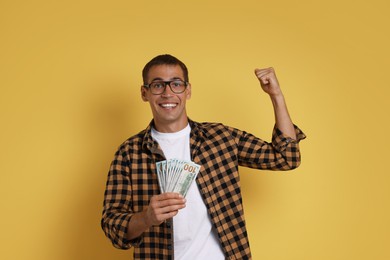 Happy man with money on yellow background