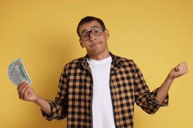 Photo of Man with dollar banknotes on yellow background