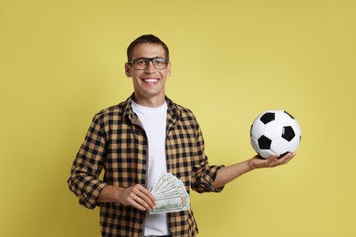 Photo of Happy man with money and soccer ball on yellow background