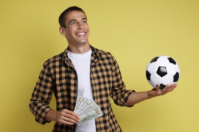 Happy man with money and soccer ball on yellow background