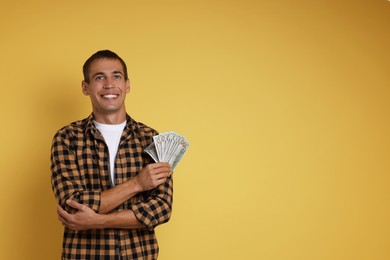 Photo of Happy man with money on yellow background, space for text