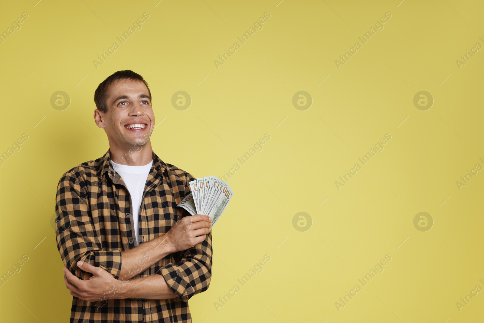 Photo of Happy man with money on yellow background, space for text