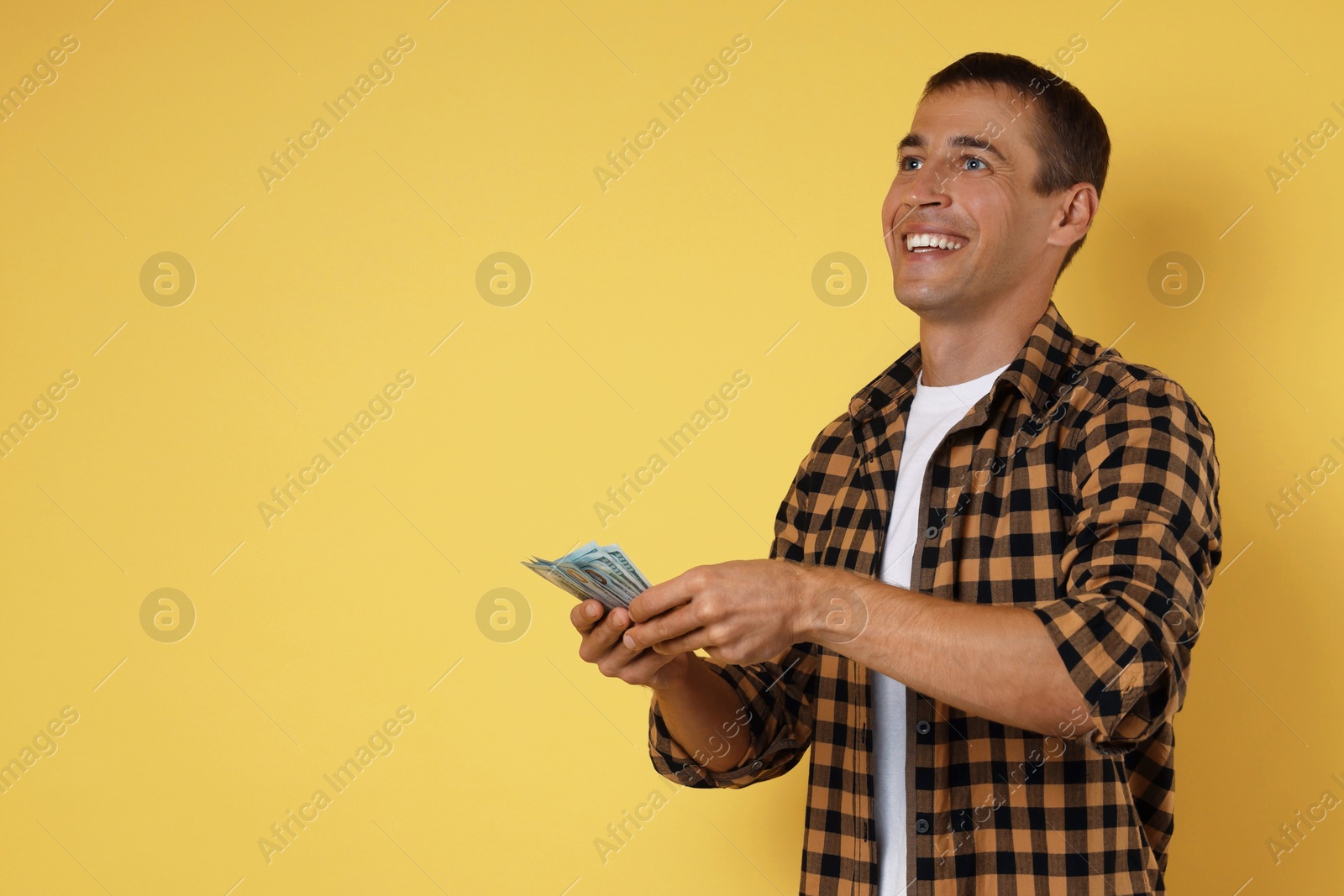 Photo of Happy man with money on yellow background, space for text