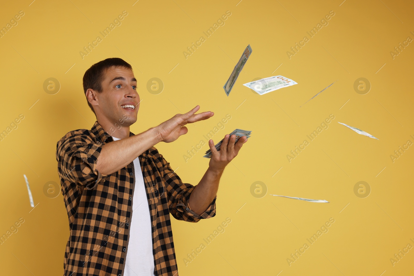 Photo of Happy man throwing money on yellow background