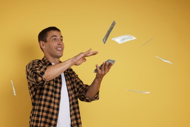 Photo of Happy man throwing money on yellow background