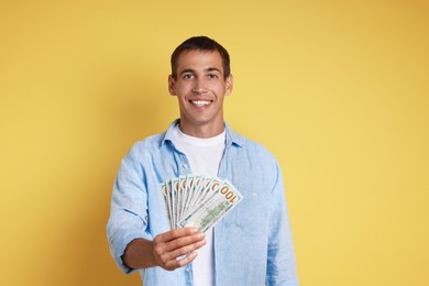 Happy man with money on yellow background