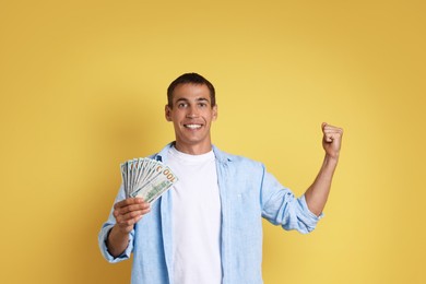 Happy man with money on yellow background