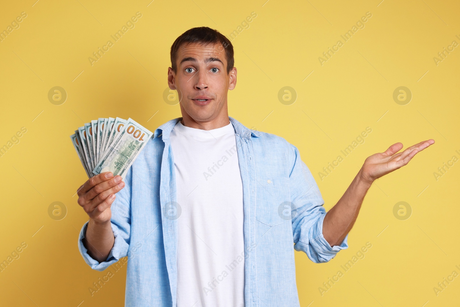 Photo of Man with dollar banknotes on yellow background