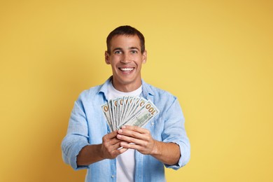 Happy man with money on yellow background