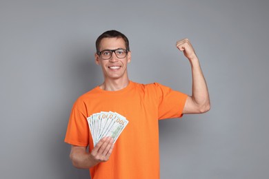 Happy man with dollar banknotes on grey background