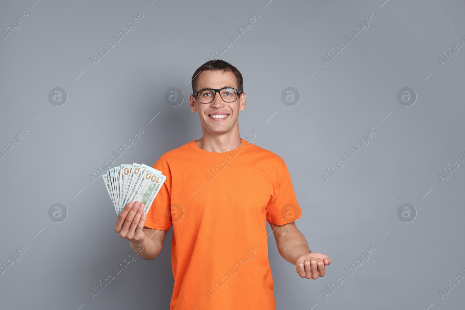 Photo of Happy man with dollar banknotes on grey background