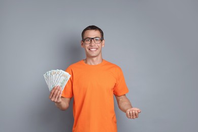 Happy man with dollar banknotes on grey background