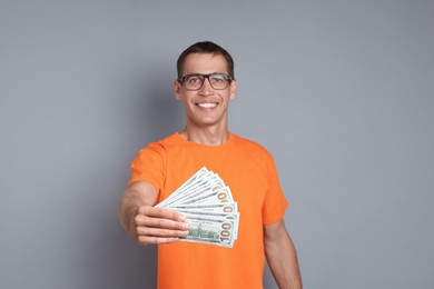 Photo of Happy man with dollar banknotes on grey background