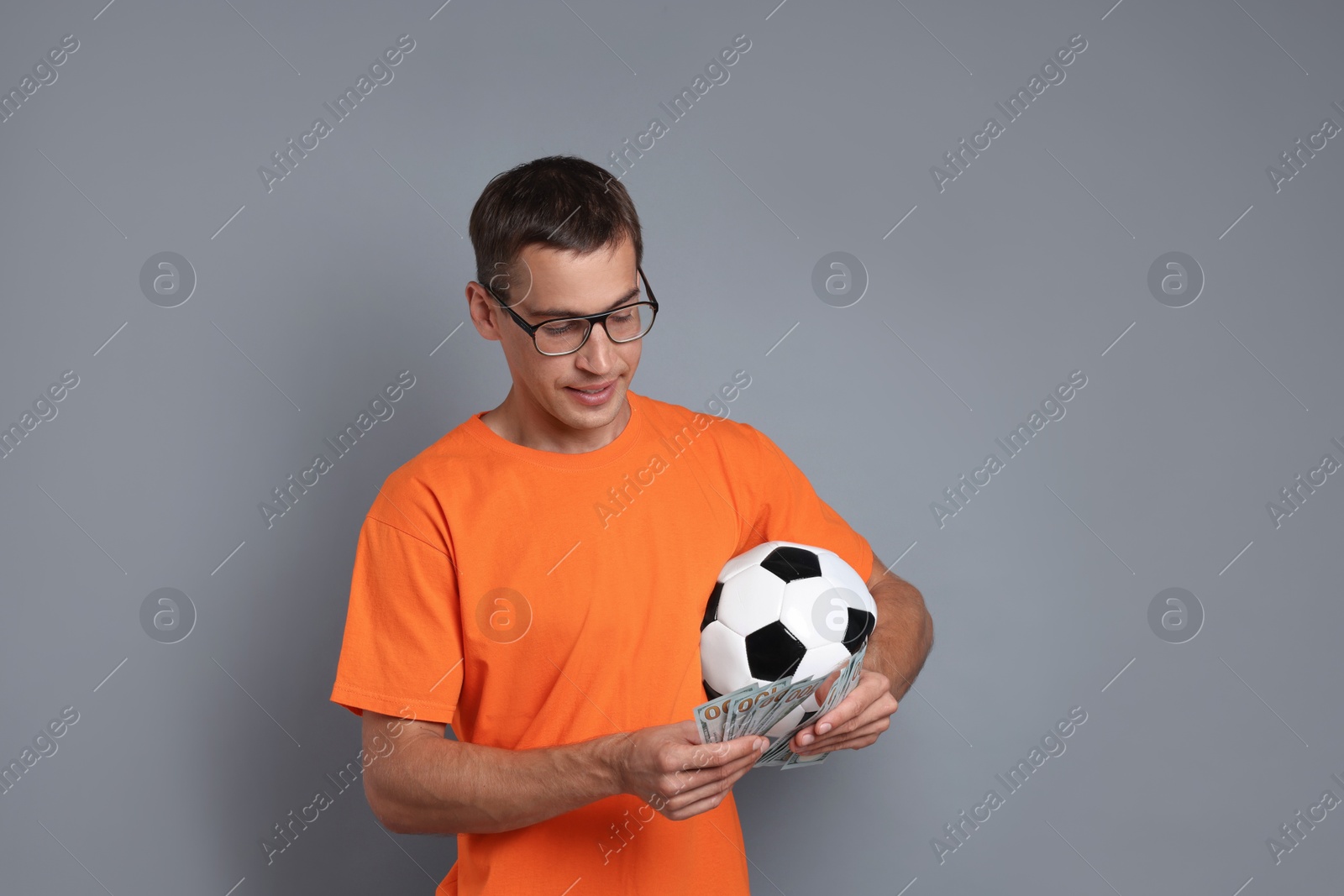 Photo of Man with money and soccer ball on grey background