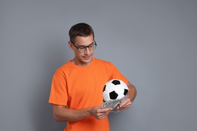 Photo of Man with money and soccer ball on grey background