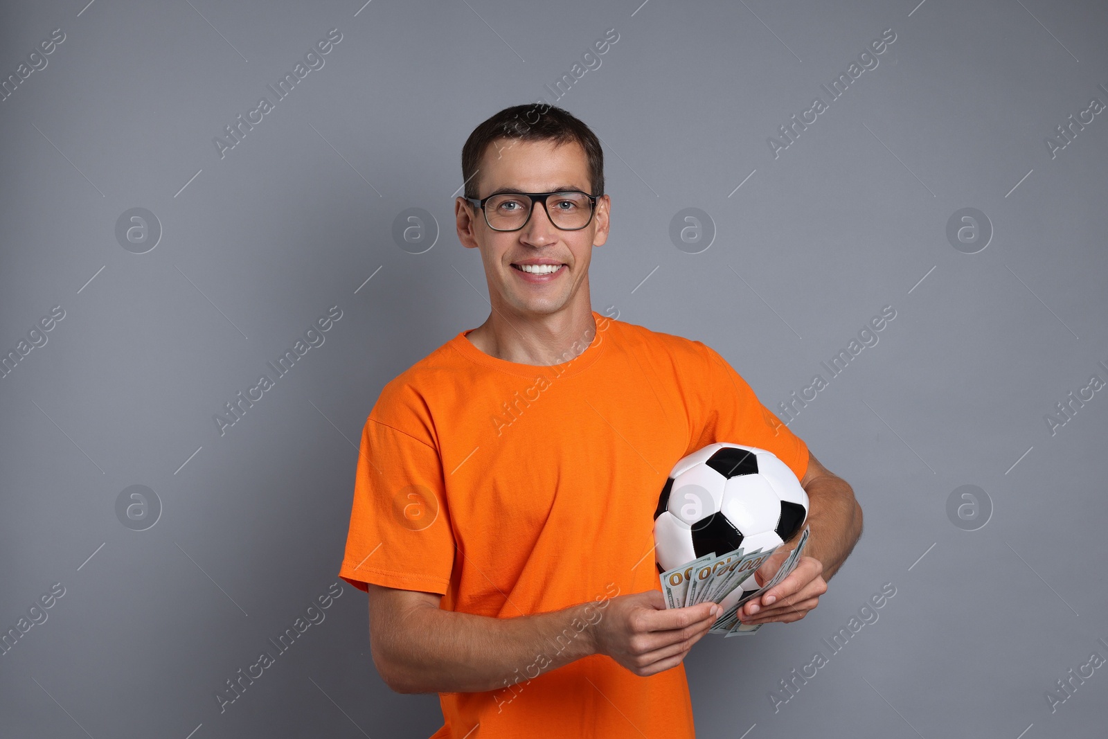 Photo of Happy man with money and soccer ball on grey background