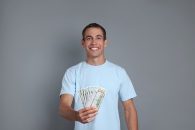 Happy man with money on grey background