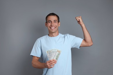 Happy man with money on grey background